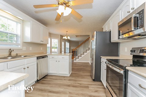 A kitchen with white cabinets and a wooden floor.