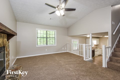 an empty living room with a fireplace and a ceiling fan