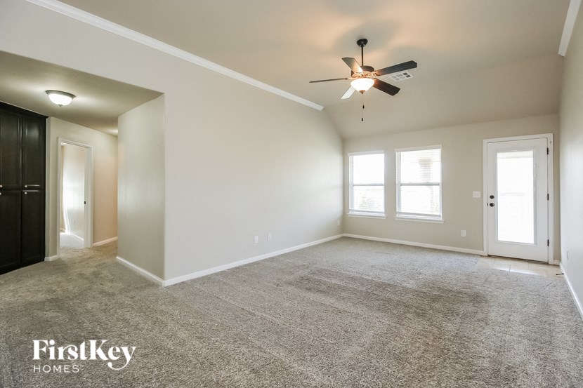 a spacious living room with carpet and a ceiling fan