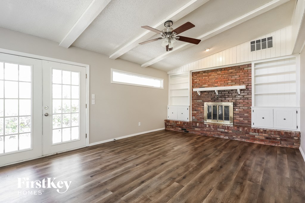 an empty living room with a fireplace and a ceiling fan