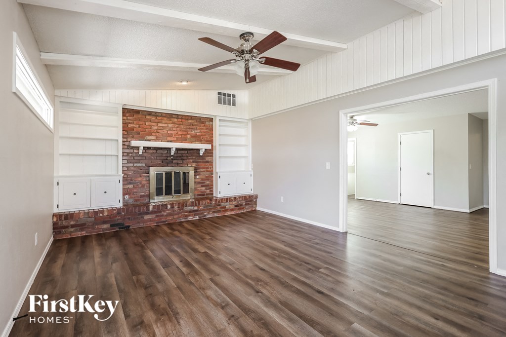 a living room with a brick fireplace and a ceiling fan