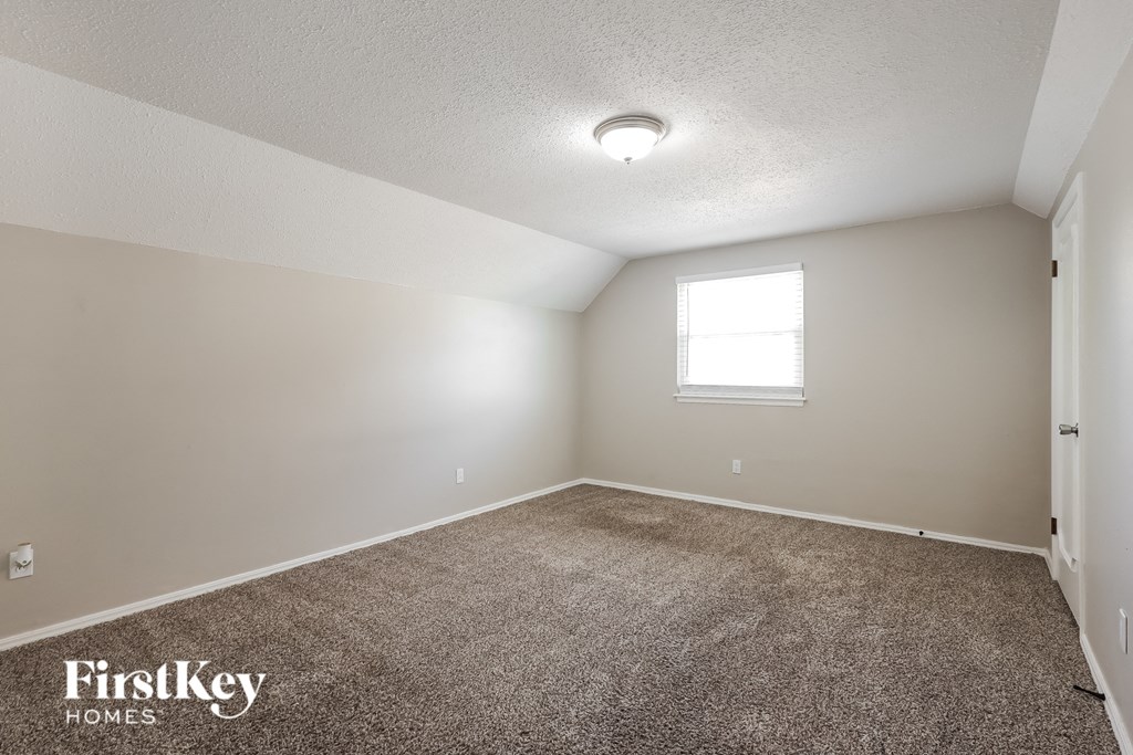the spacious living room with carpeting and a window