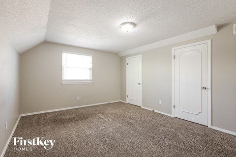 the spacious living room with carpet and a door to the bedroom