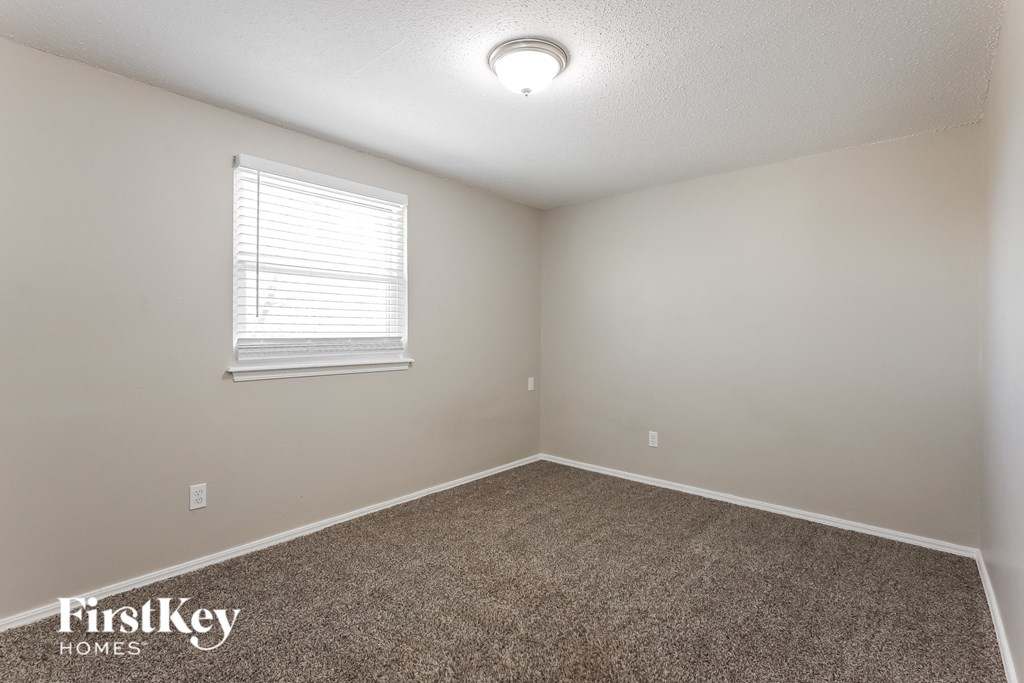 the upstairs bedroom has a carpeted floor and a window