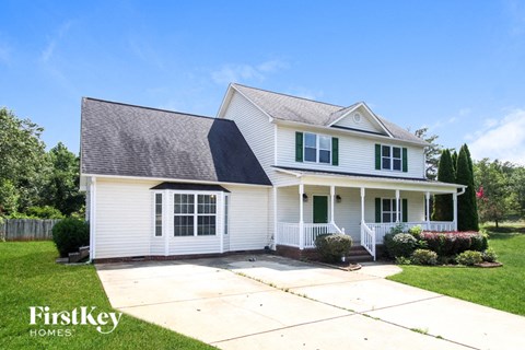 a white house with green shutters and a driveway