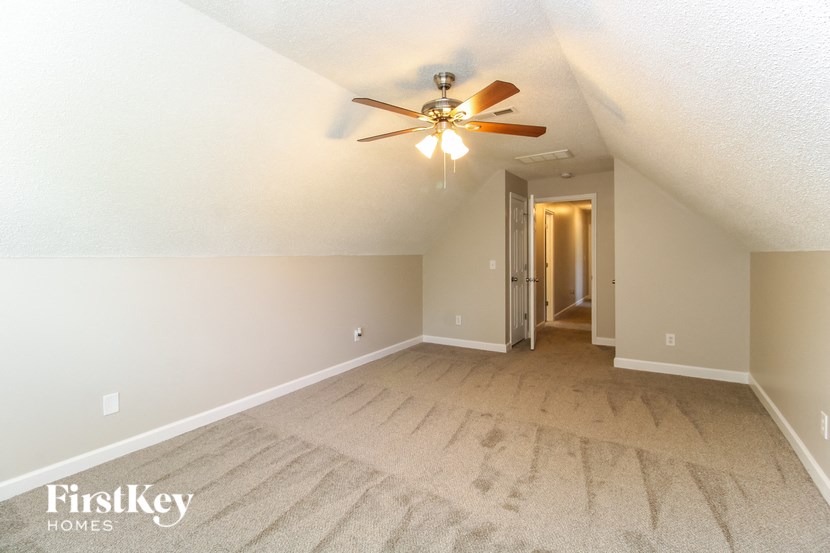 a living room with a ceiling fan and a carpet