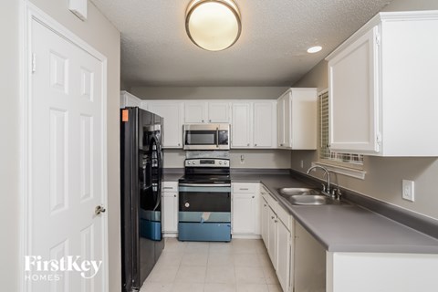 A kitchen with a black fridge and white cabinets.