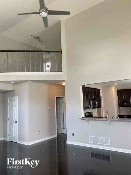 an empty room with a ceiling fan and a kitchen