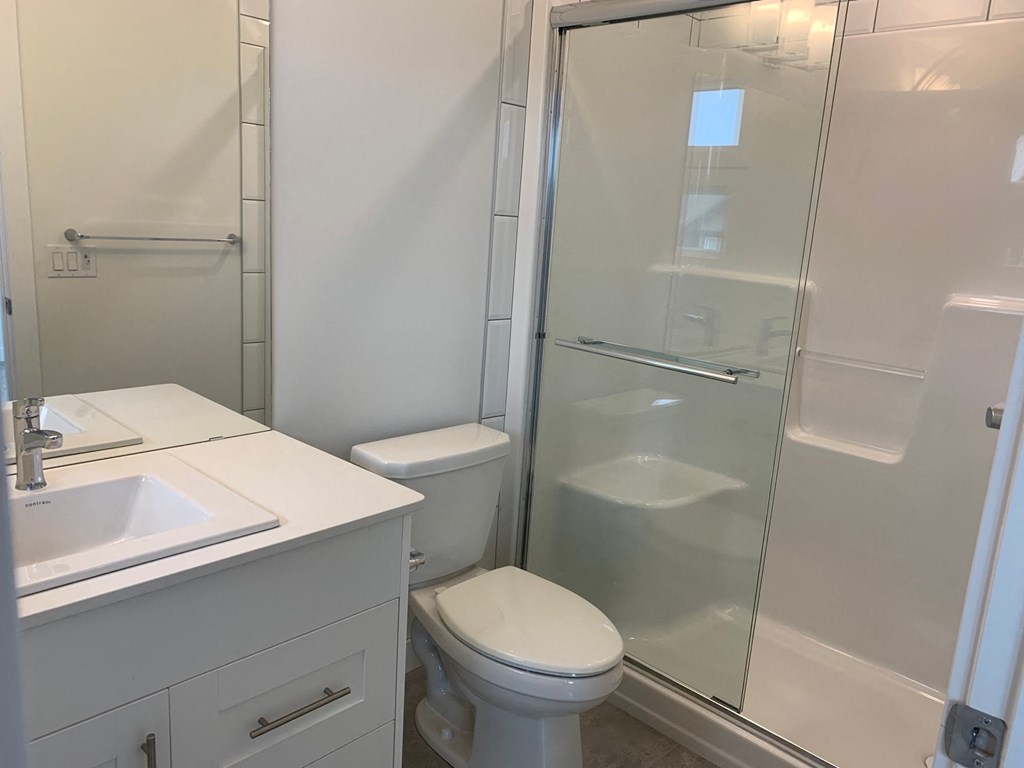 a white bathroom with a shower toilet and sink