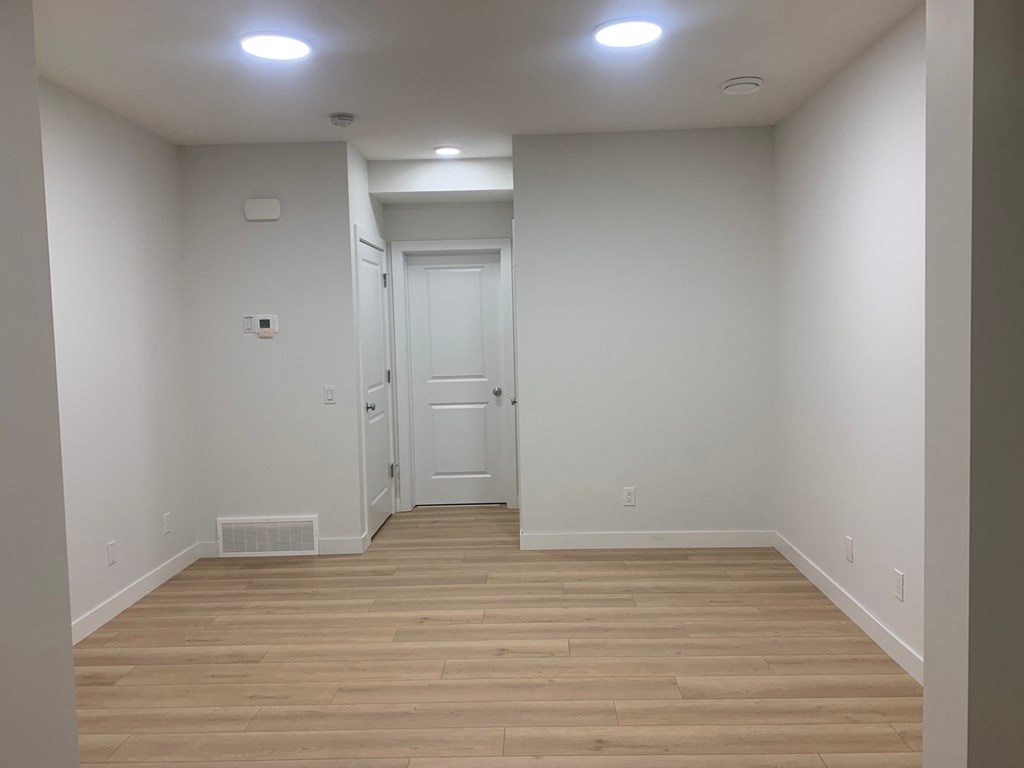 a hallway with wood floors and white walls and a door