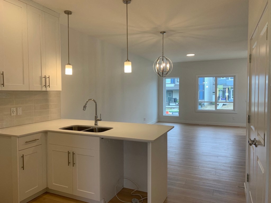an empty kitchen with white cabinets and a sink