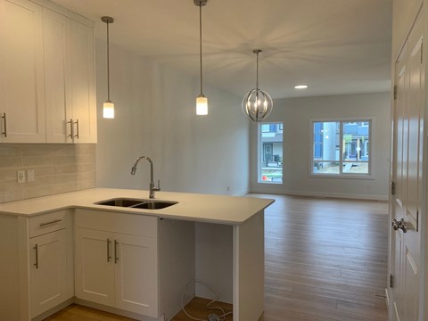 an empty kitchen with white cabinets and a sink
