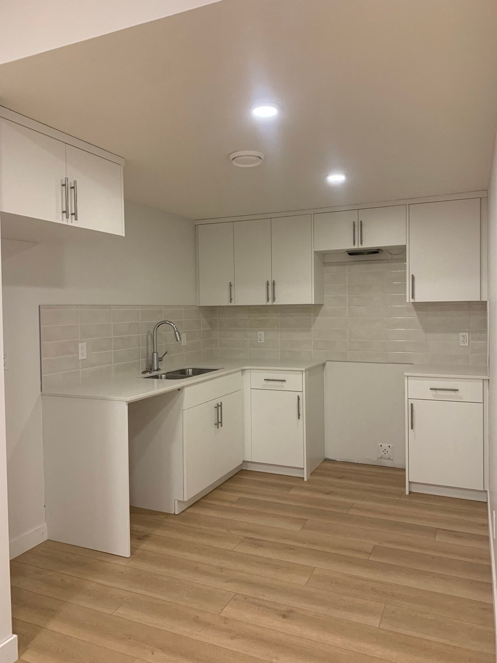 an empty kitchen with white cabinets and a sink