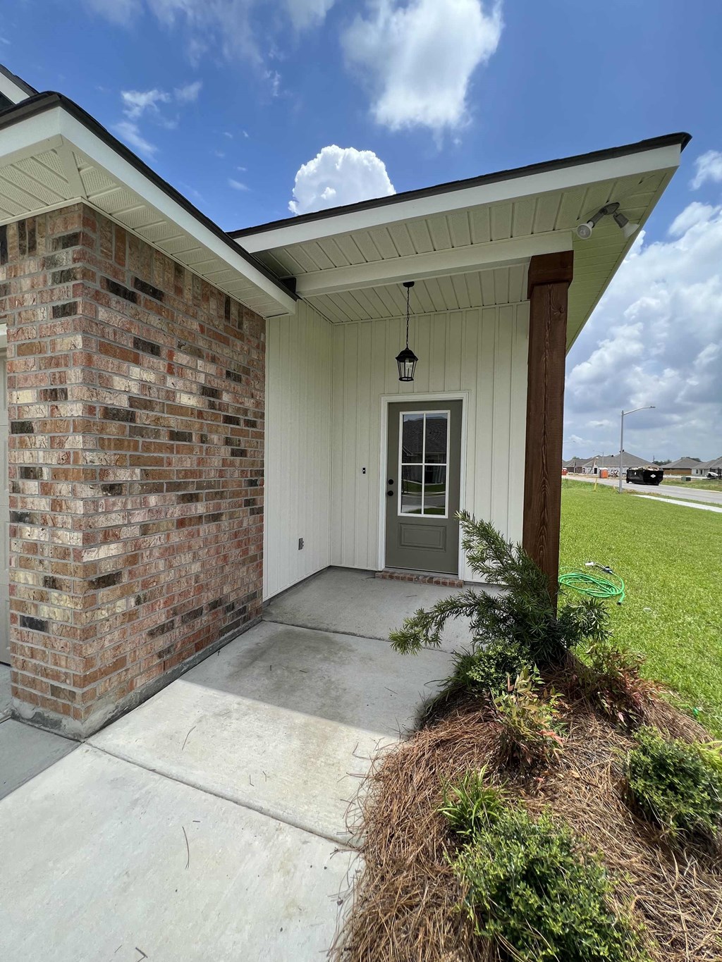 the front door of a building with a concrete sidewalk and a brick wall