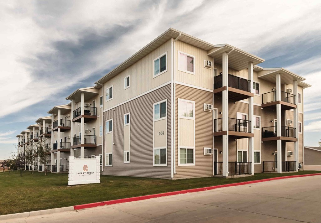 an exterior view of an apartment building with a sign in front of it