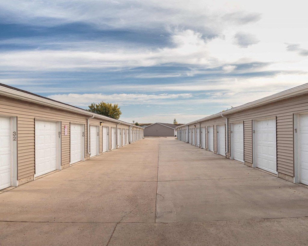 a row of storage sheds with white doors and a blue cloudy sky