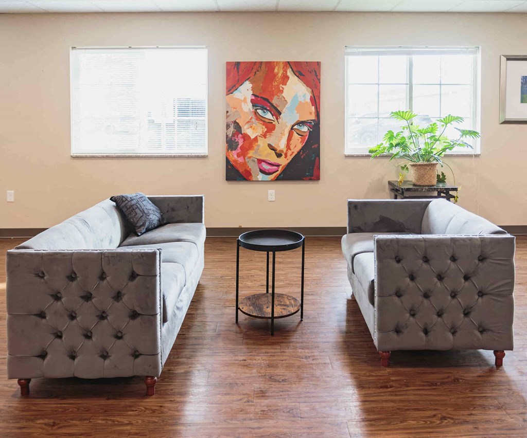 a living room with couches and chairs and a painting on the wall