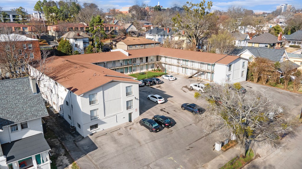 an aerial view of a white building with a red roof and a parking lot