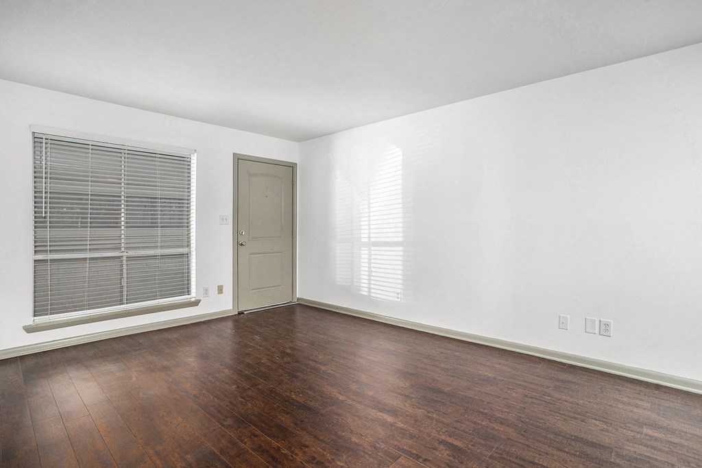 an empty living room with wood flooring and a window and a door
