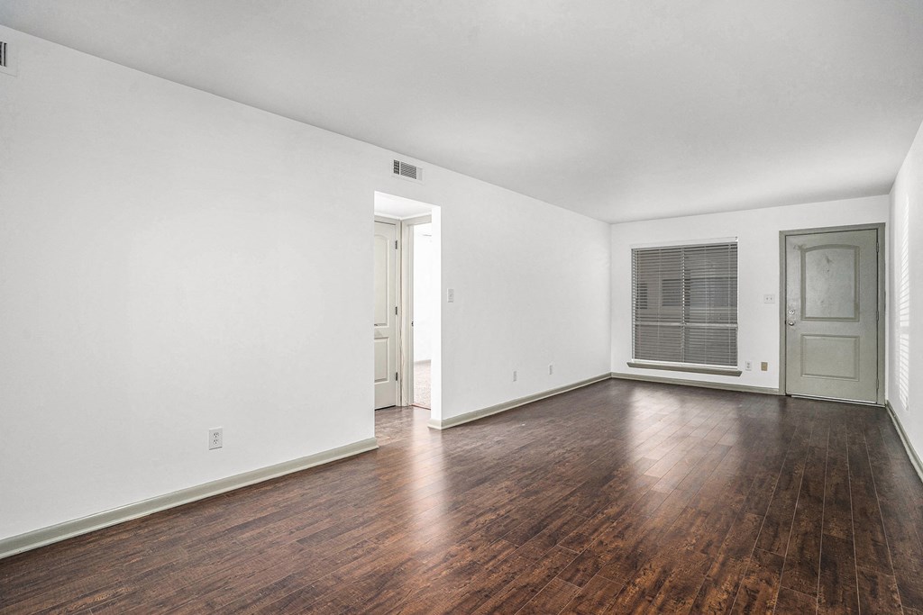 an empty living room with wood floors and white walls