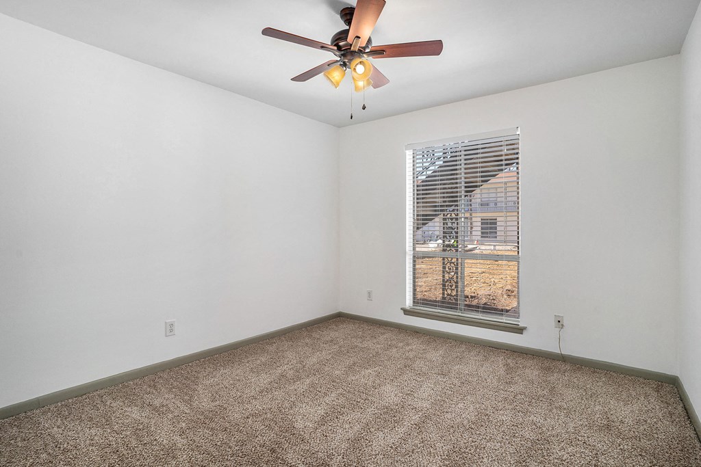 an empty room with a ceiling fan and a window