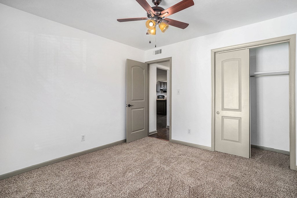an empty room with a ceiling fan and a door to a bathroom