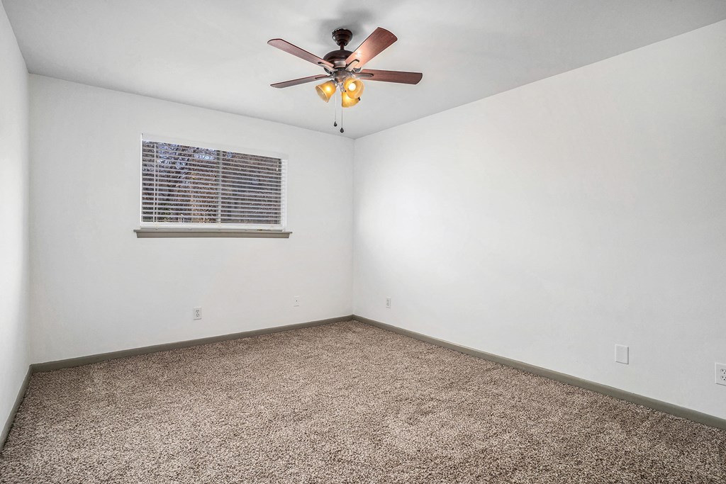 an empty room with a ceiling fan and a window