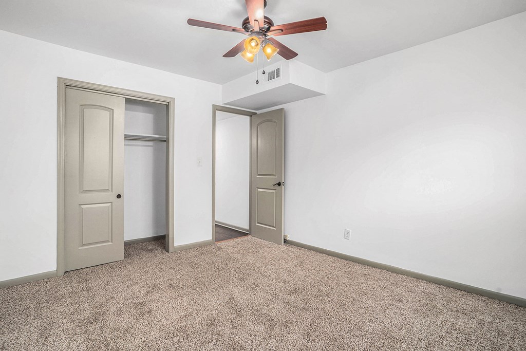 a room with white walls and a ceiling fan and two doors