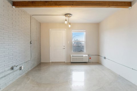 an empty living room with a white brick wall and a window