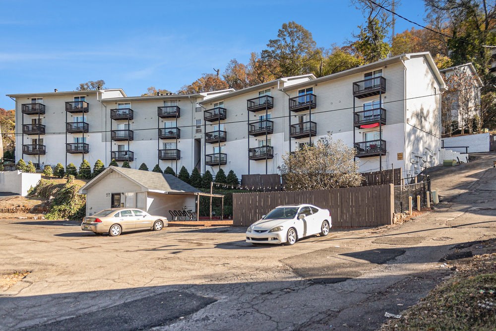an apartment building with two cars parked in front of it