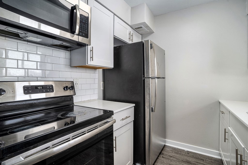 a kitchen with white cabinets and black appliances and a refrigerator