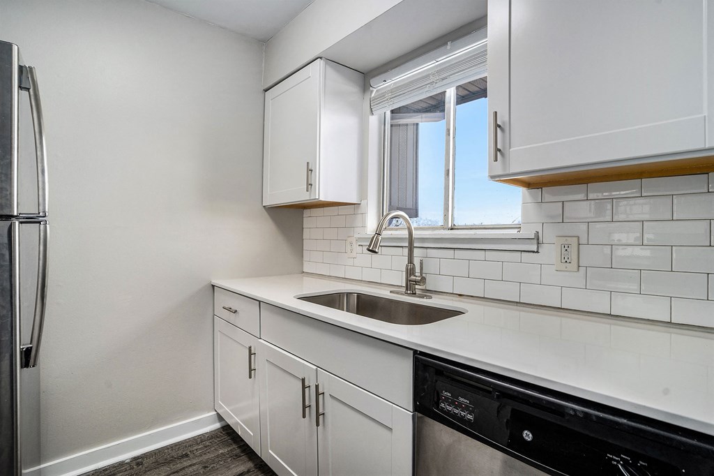 an empty kitchen with white cabinets and a sink and a window