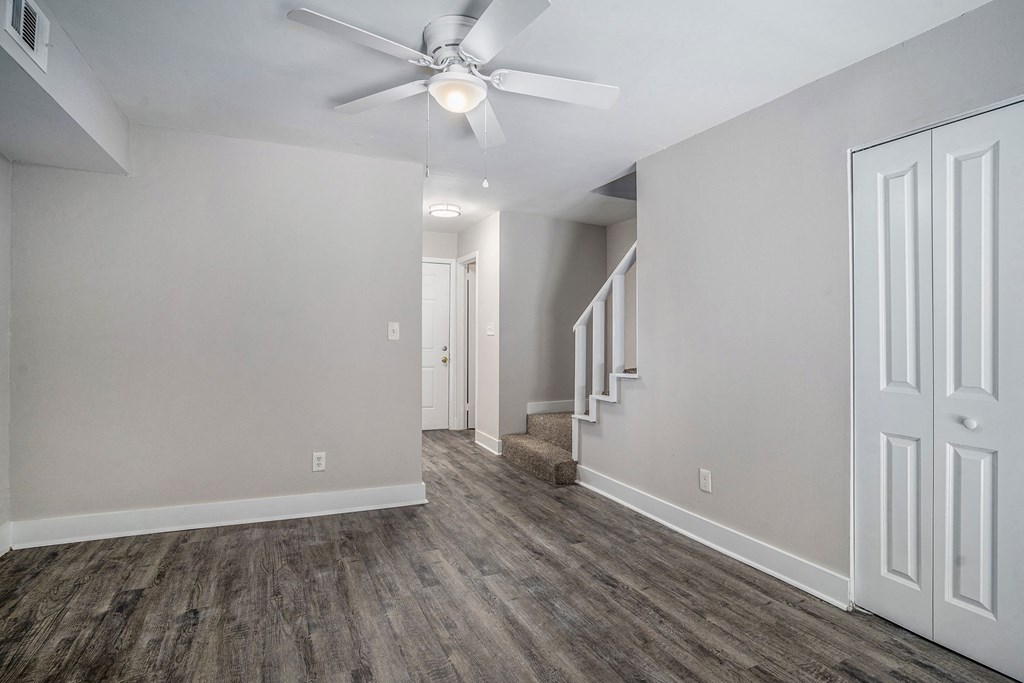 the living room and dining room of an empty house with a ceiling fan