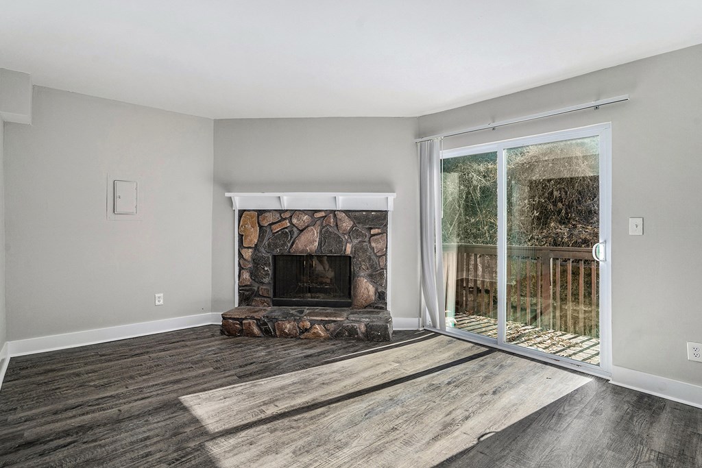 an empty living room with a fireplace and a sliding glass door