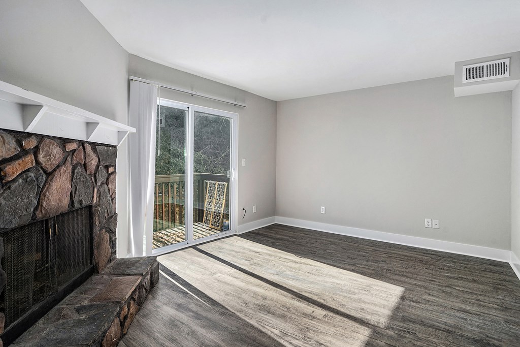an empty living room with a fireplace and a sliding glass door