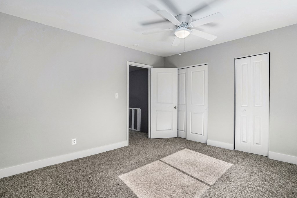 an empty room with carpet and a ceiling fan