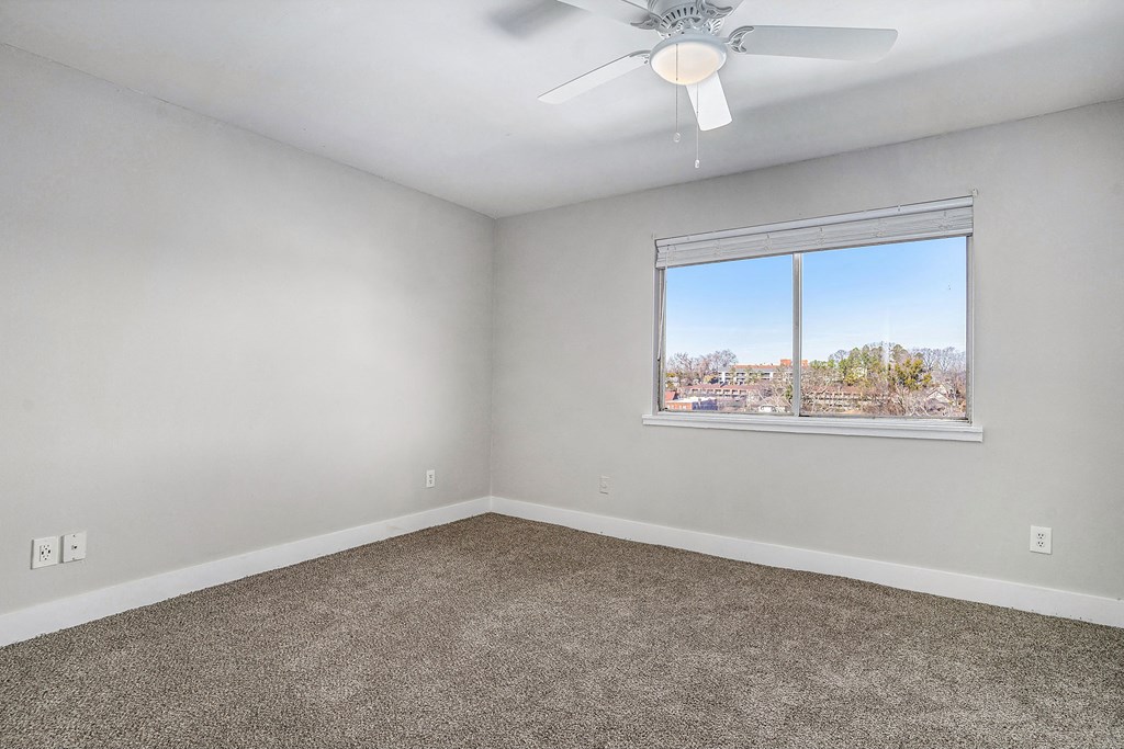 an empty room with a window and a ceiling fan