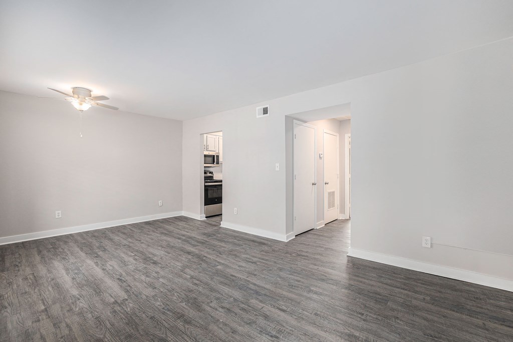 a living room with white walls and wood flooring and a ceiling fan