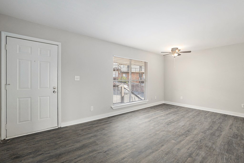an empty living room with a large window and a white door