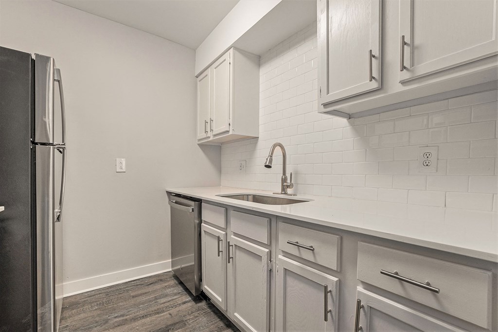 an empty kitchen with white cabinets and a stainless steel refrigerator