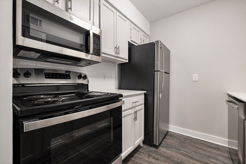 a kitchen with black appliances and white cabinets and a refrigerator