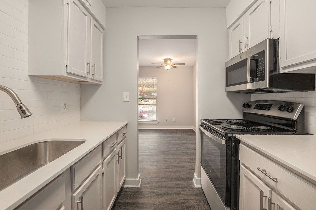 a kitchen with white cabinets and black appliances and a window
