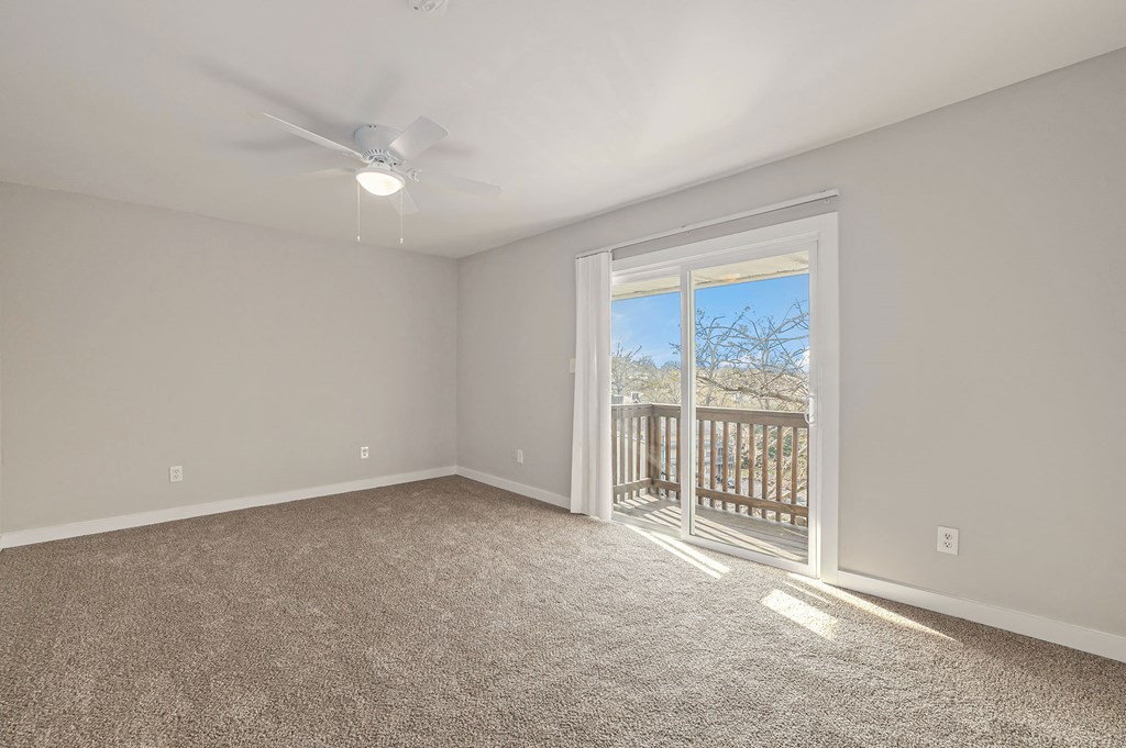 an empty living room with a sliding glass door to a balcony