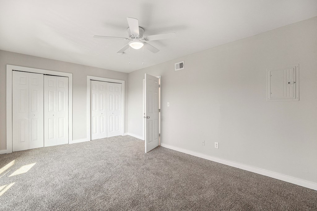 an empty room with carpet and a ceiling fan