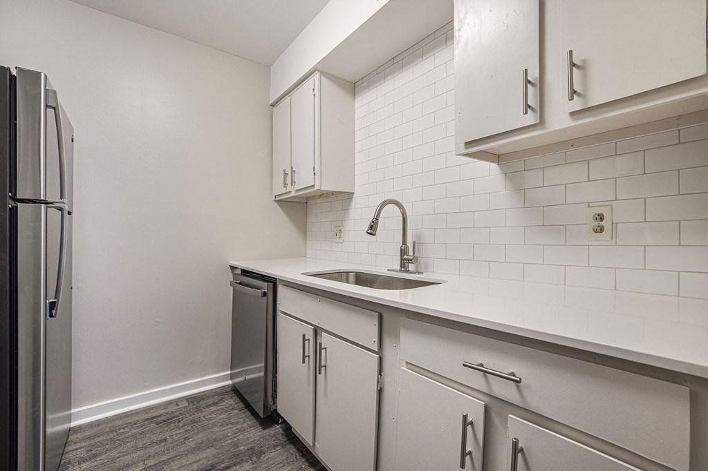 an empty kitchen with white cabinets and a stainless steel refrigerator