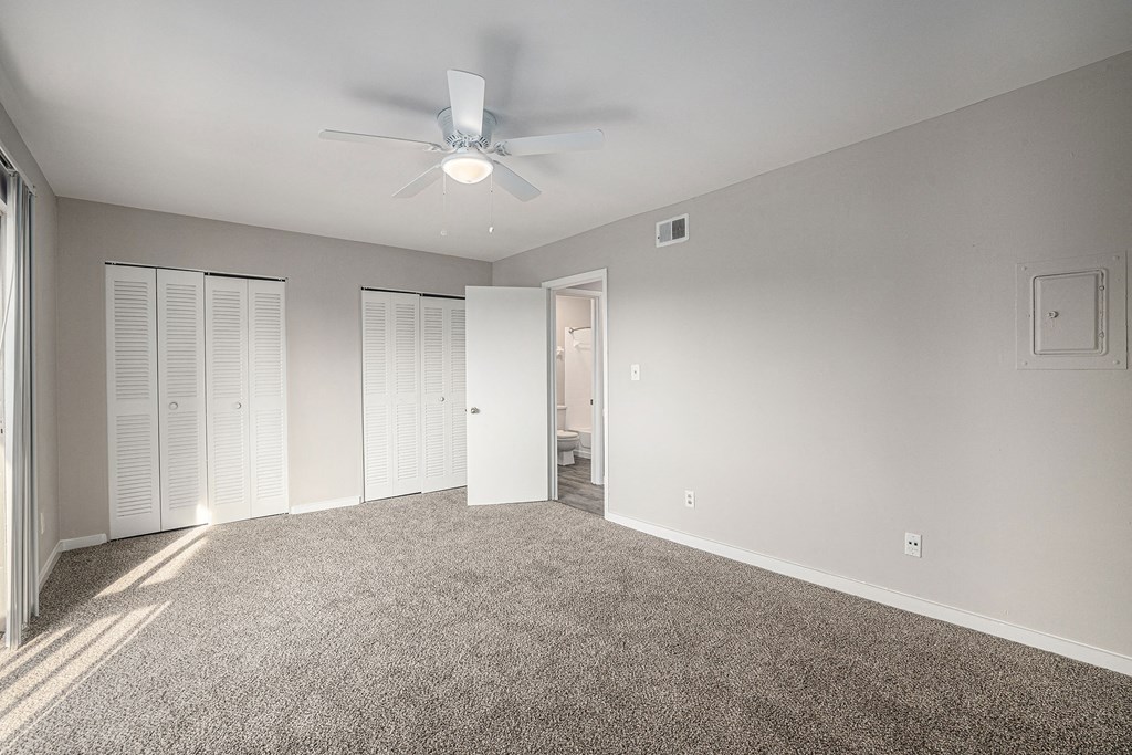 an empty living room with carpet and a ceiling fan