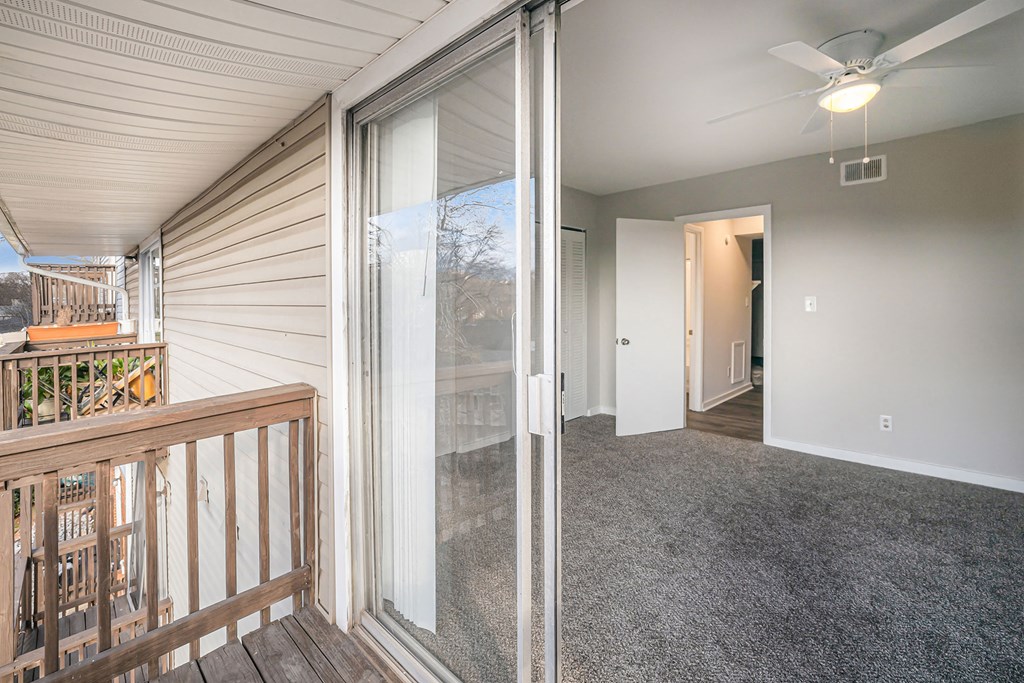 view of living room from balcony with sliding glass doors and carpeted flooring
