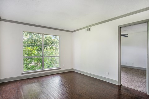 an empty living room with a large window and wooden floors