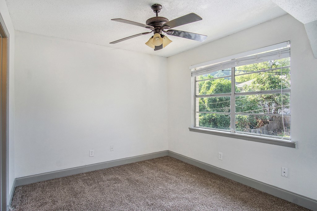 an empty room with a ceiling fan and a window