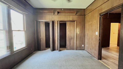 a living room with grey carpet and wooden walls and doors
